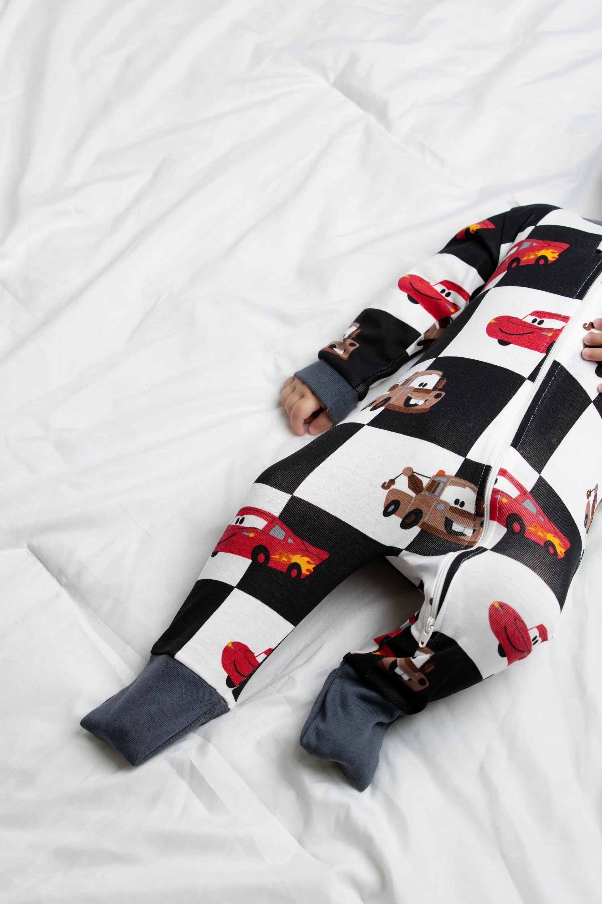 Children's onesie with car and checkered pattern on a white surface