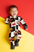 Child wearing a black and white checkered onesie with car designs on a red and yellow background