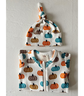 A baby knit hat and matching zip-front bodysuit set with an all-over pumpkin print in orange, teal, and brown on a white background, displayed against a light textured wall.