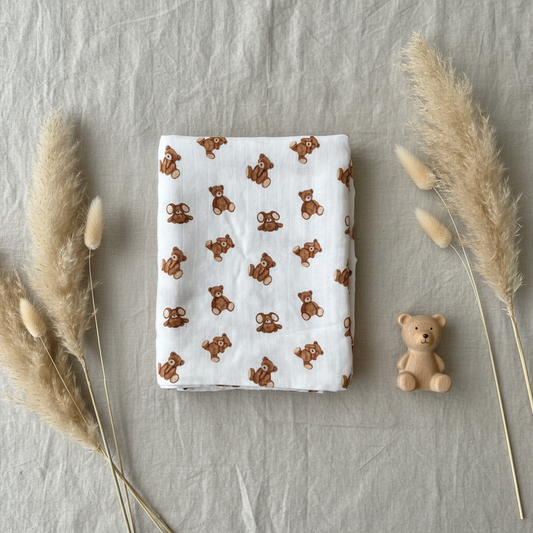 Cuddle Teddy Bear Muslin Swaddle flat lay with wooden toy bear and pampas grass